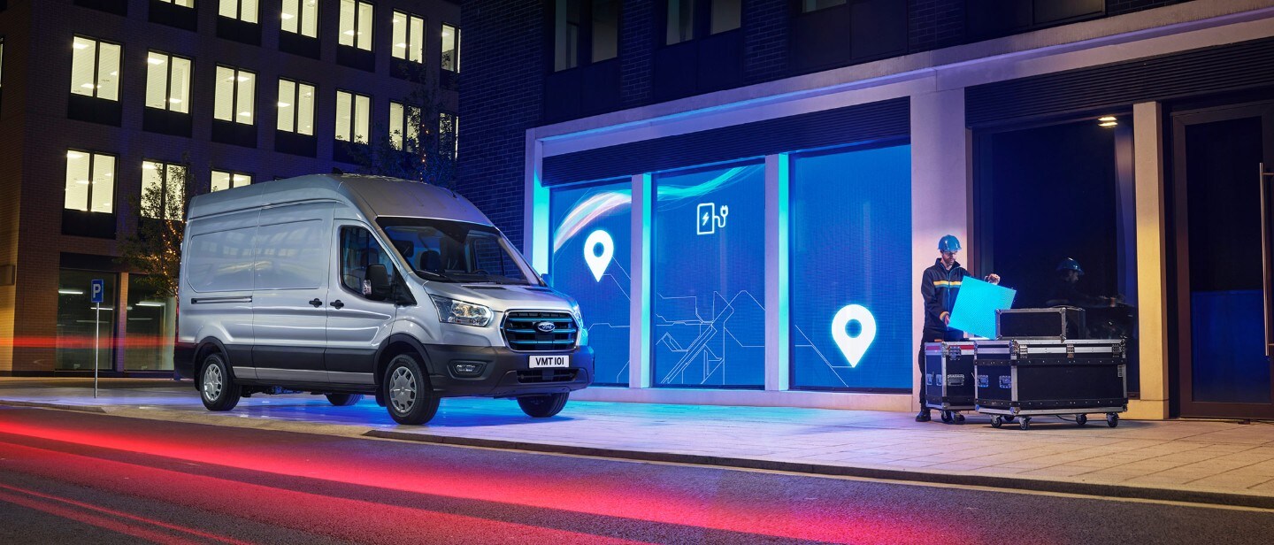 New Ford E-Transit in front of depot in city in night 3/4 front view