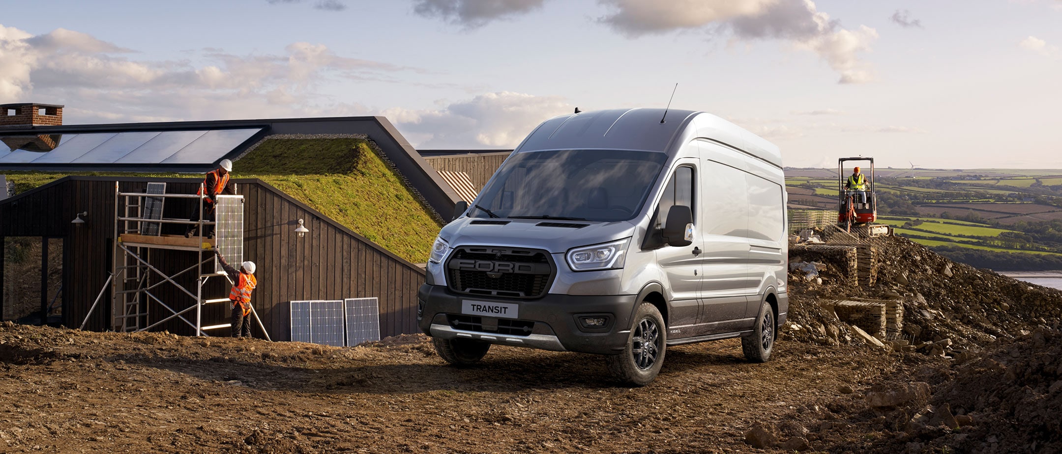 Stříbrný Ford Transit parkující vedle rozestavěného domu