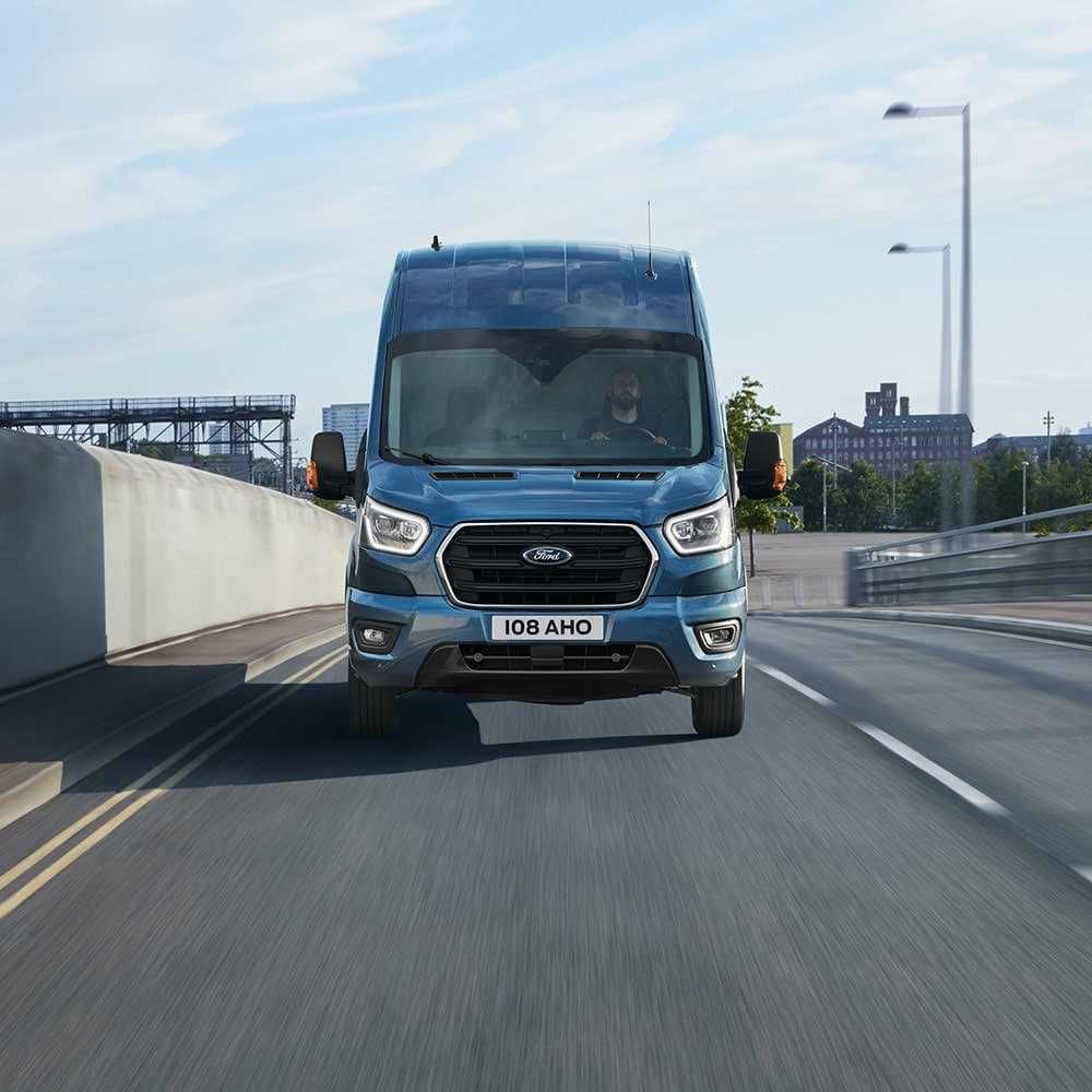 Modrá dodávka Ford Transit jede po víceproudé silnici