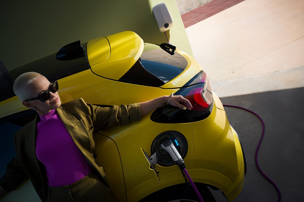 Pohled zblízka na zadní část elektrického Fordu Puma Gen-E® připojeného k domácí nástěnné nabíječce. 