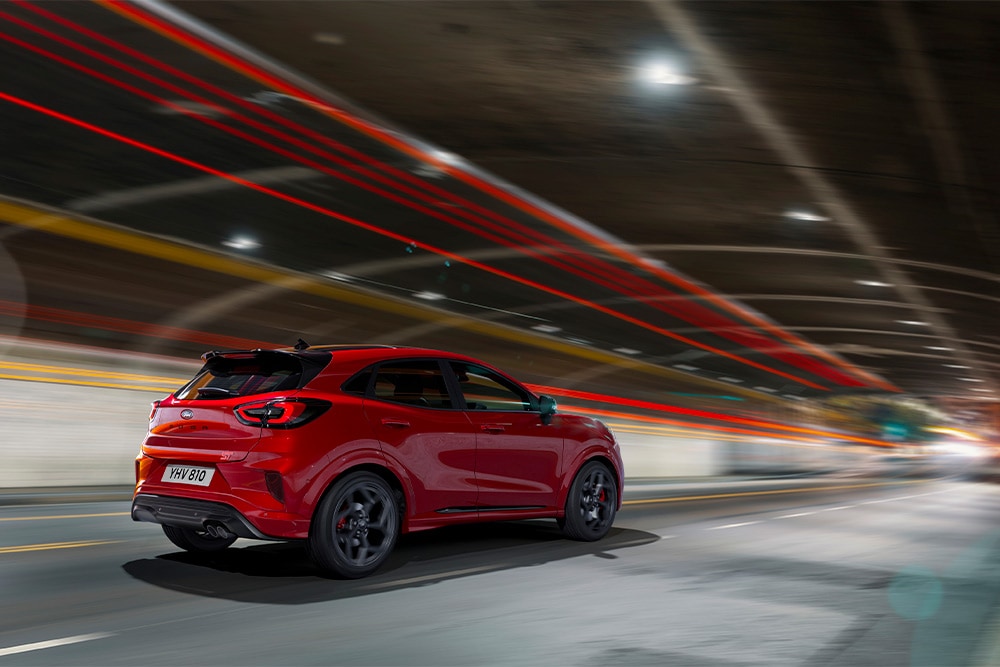 Červený mild-hybridní vůz Ford Focus projíždějící tunelem.