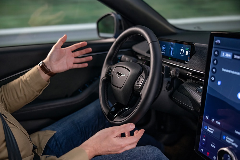 Osoba na sedadle řidiče automobilu s rukama mimo volant.
