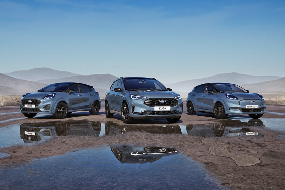 Ford Puma, Ford Kuga a Ford Puma Gen-E stojí zaparkované na mokré silnici, v pozadí jsou hory.