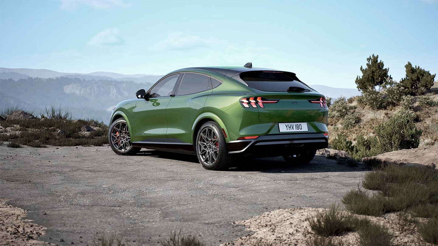 Zadní část Fordu Mustang Mach-E GT v barvě zelená Eruption, parkuje na horské silnici.