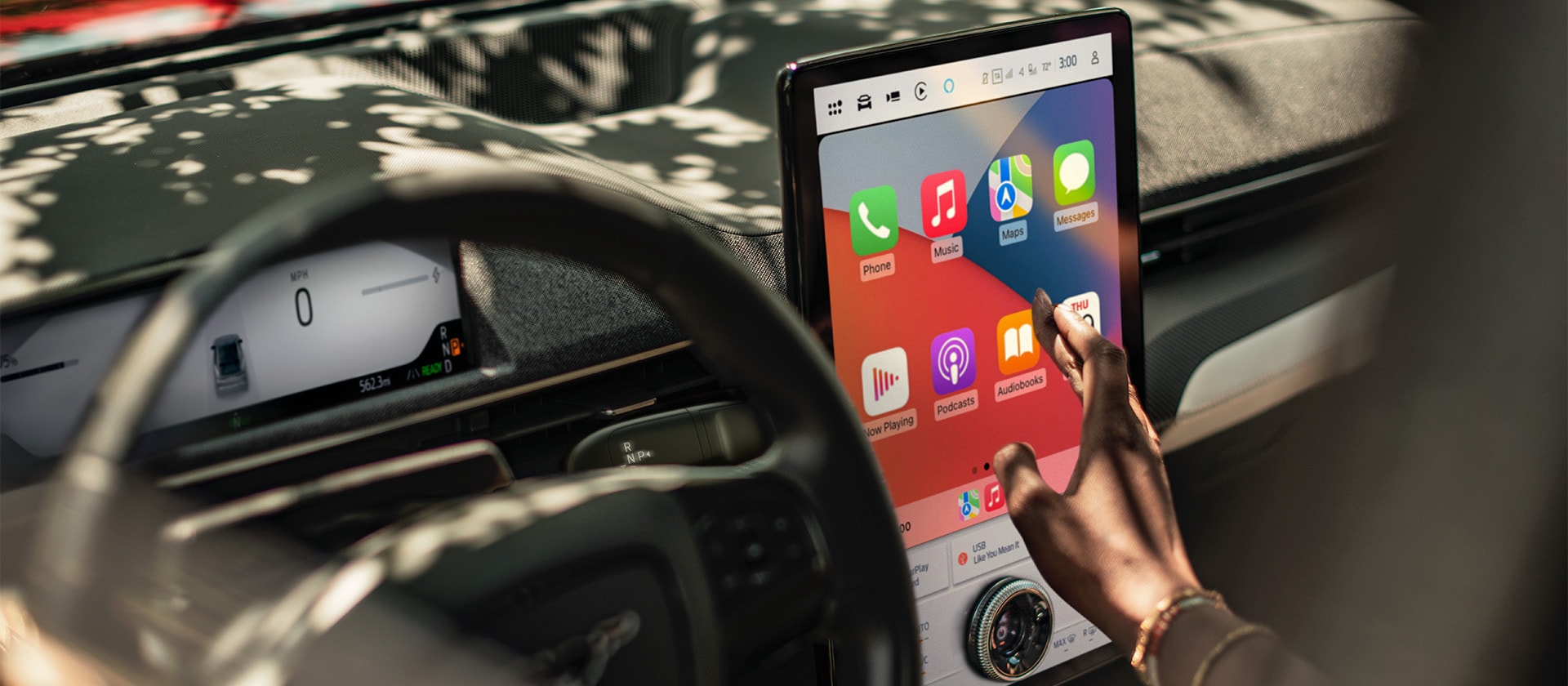 Detailní záběr na řidiče Fordu Mustang Mach-E, který na velké 15,5" dotykové obrazovce SYNC 4 používá Apple CarPlay. 