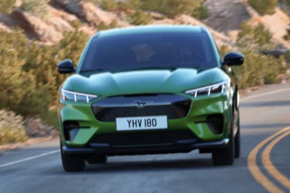Přední pohled na zelený Ford Mustang Mach-E na horské silnici.