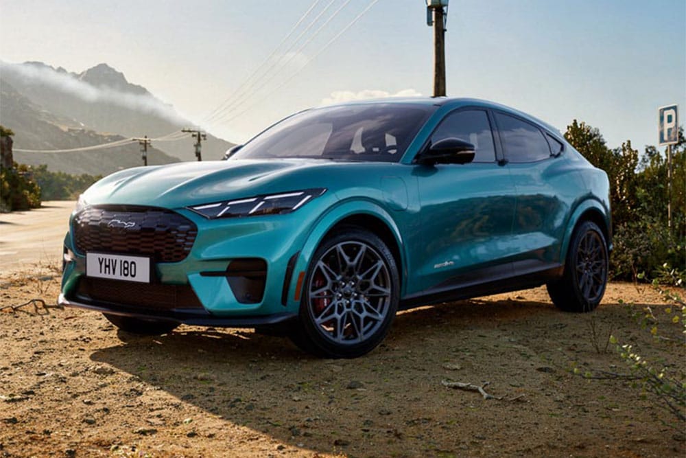 Detailní záběr na stylový Ford Mustang Mach-E GT, s jedinečným znakem GT na designové voštinové přední mřížce.