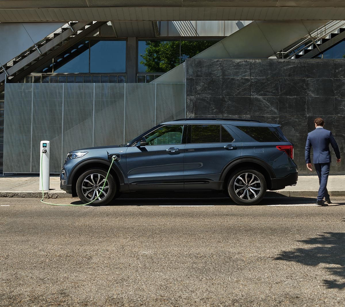 Boční pohled na Ford Explorer PHEV zaparkovaný u nabíjecí stanice