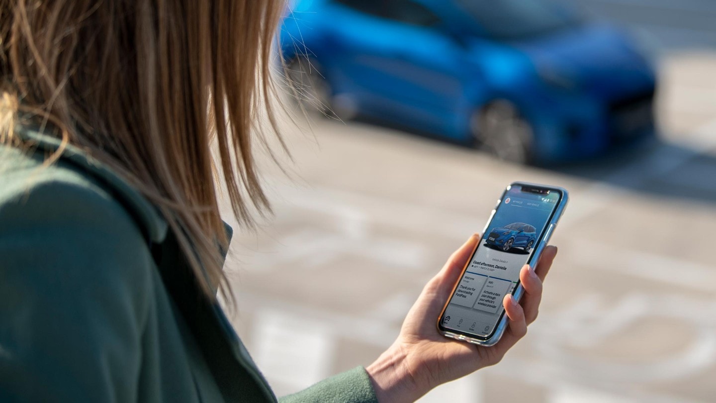 A woman holding mobile phone with FordPass App