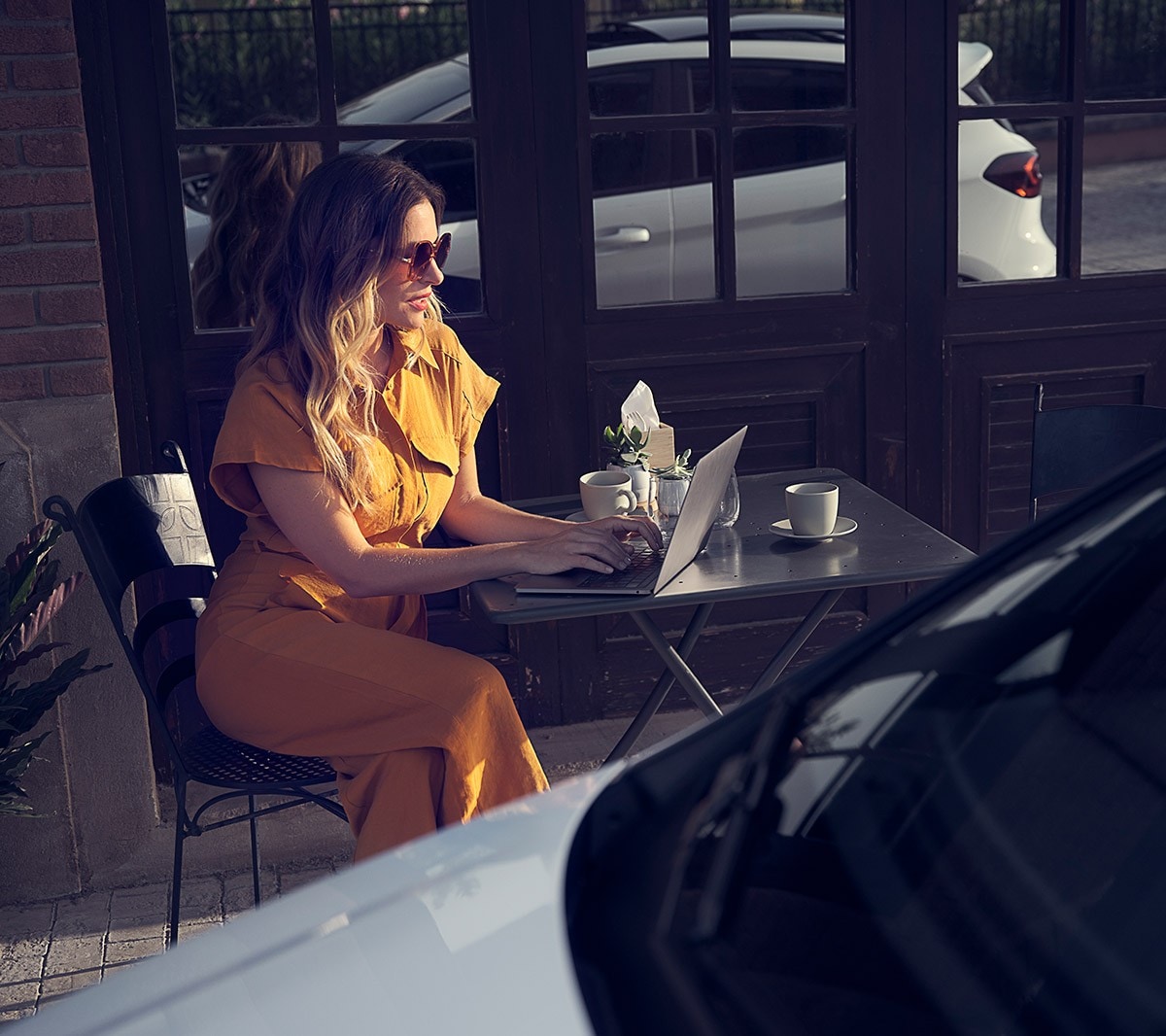 Ford Fiesta se ženou sedící před kavárnou