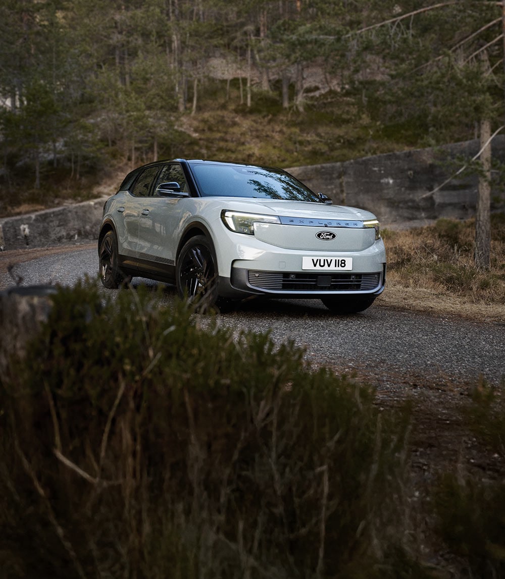 Stříbrný Ford Explorer jedoucí po horské cestě. 