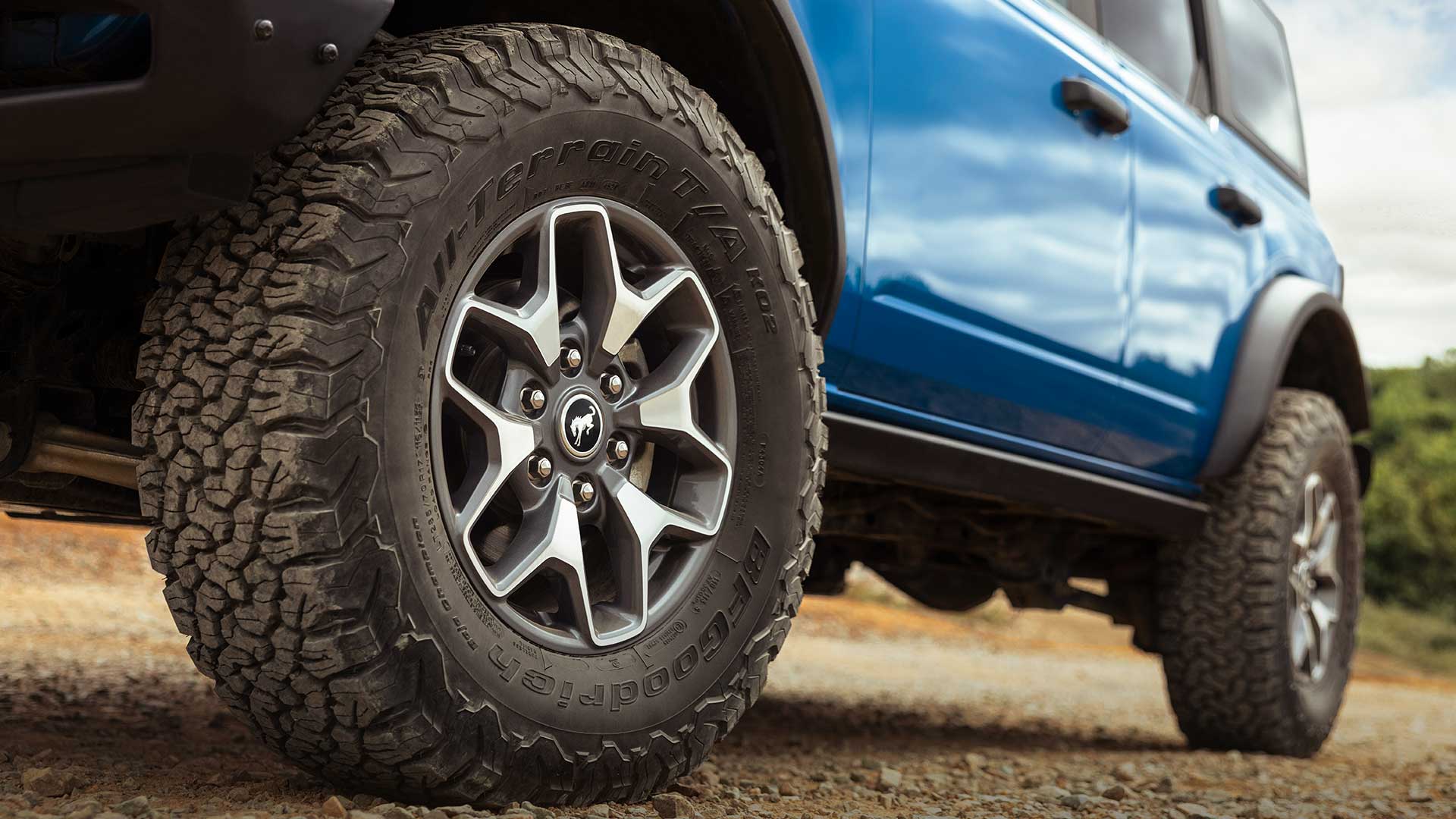 Detailní pohled na terénní pneumatiky modrého Fordu Bronco.