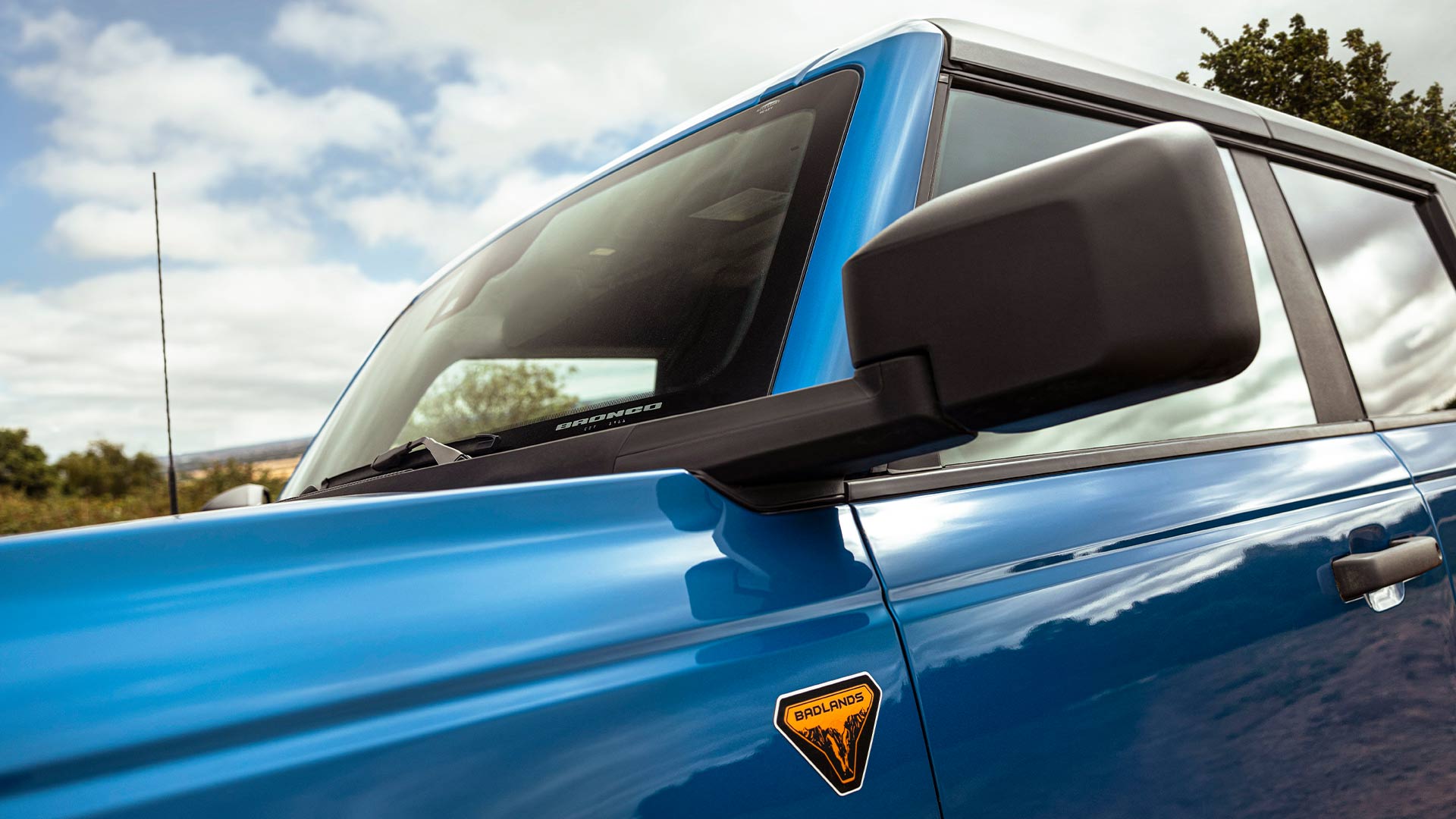 Detailní záběr na zpětné zrcátko na boku modrého Fordu Bronco.