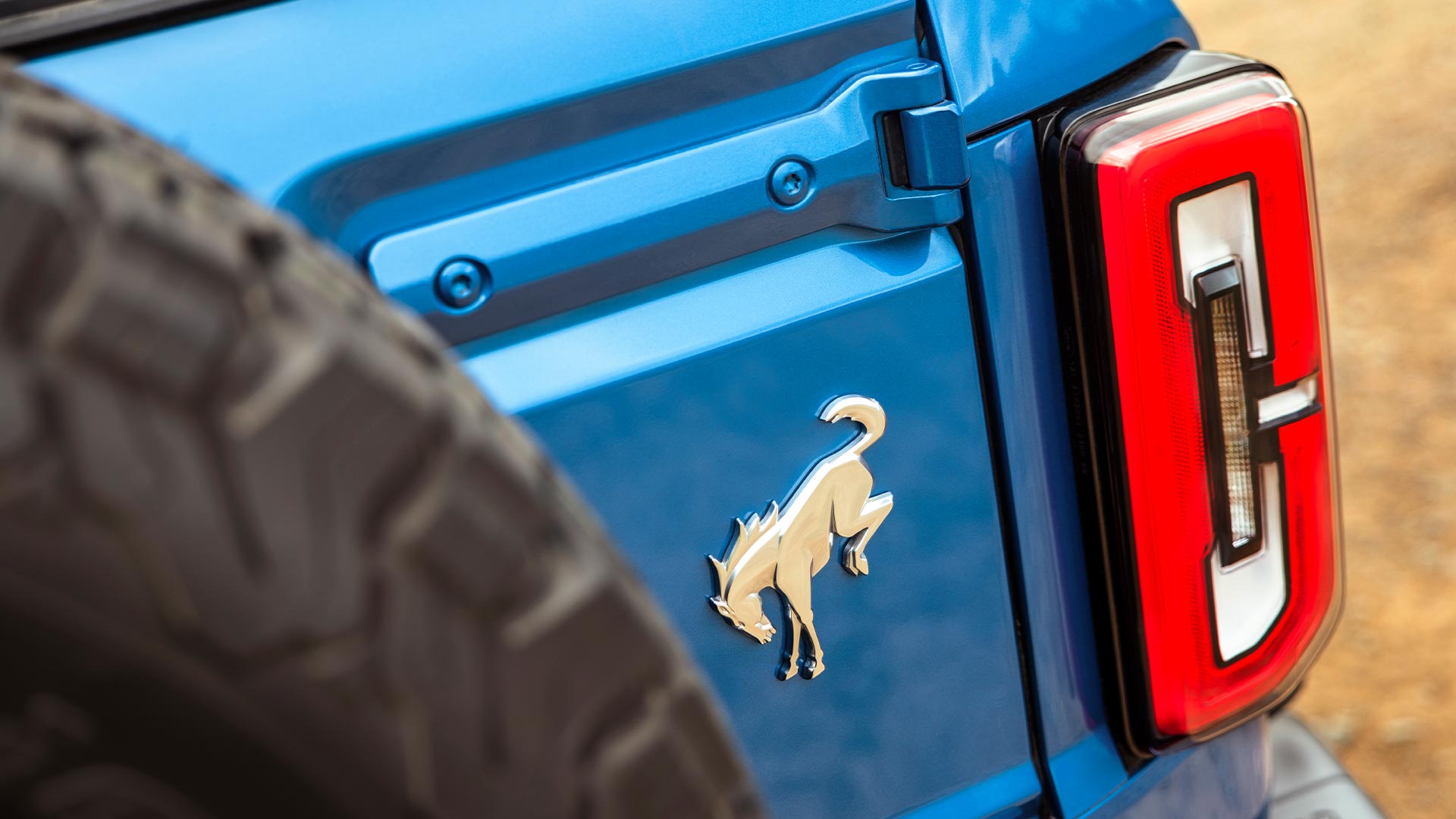 Detailní záběr na značkové detaily na zadní straně modrého Fordu Bronco.