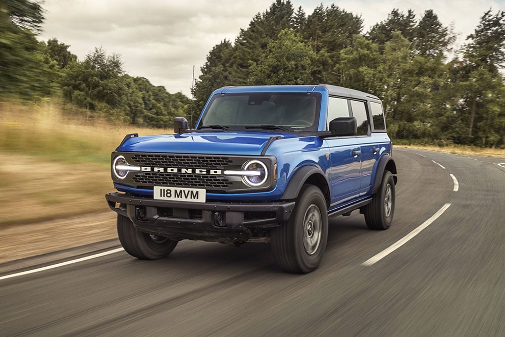 Pohled zepředu na nový Ford Bronco v modré barvě při jízdě v terénu.