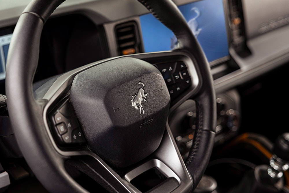 Detailní záběr na značkový kožený volant Fordu Bronco.
