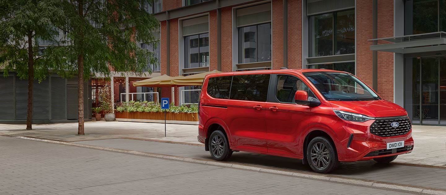 Červený Ford Tourneo Custom parkující na ulici ve městě.