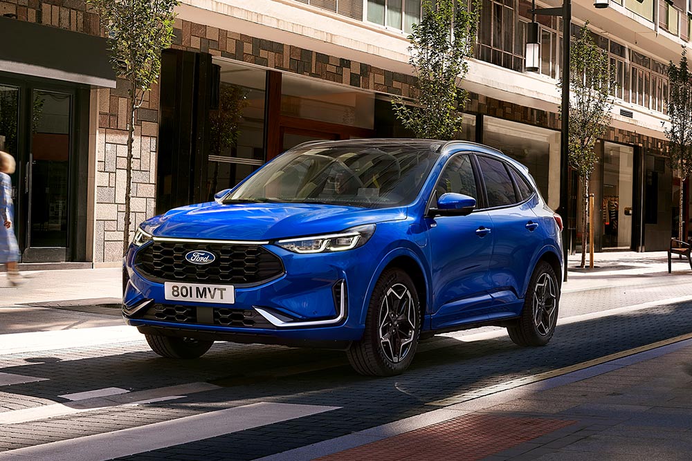 Modrý Ford Kuga jedoucí po městské ulici.