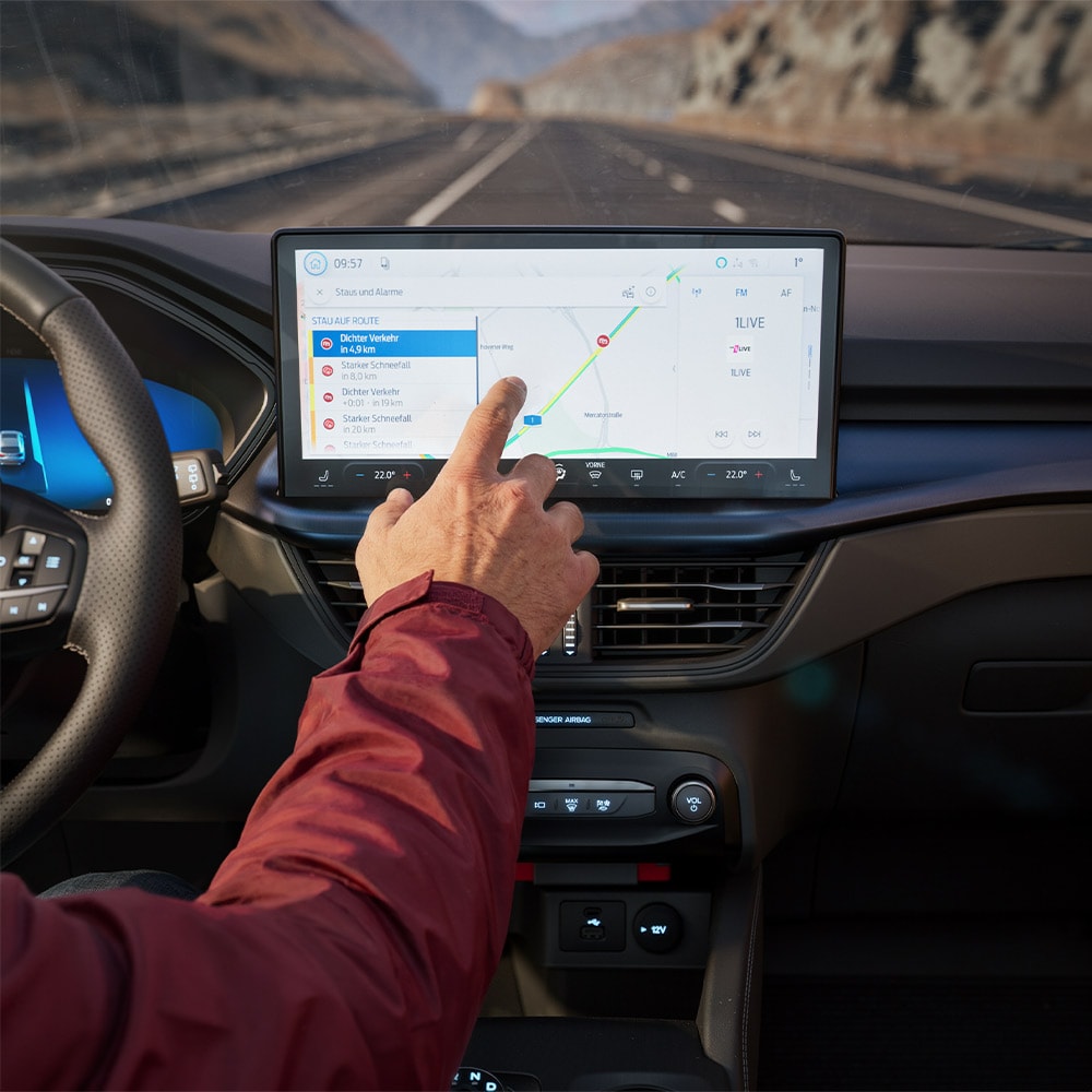 Řidič používá online navigaci na digitální obrazovce ve voze Ford Kuga BlueCruise Edition.