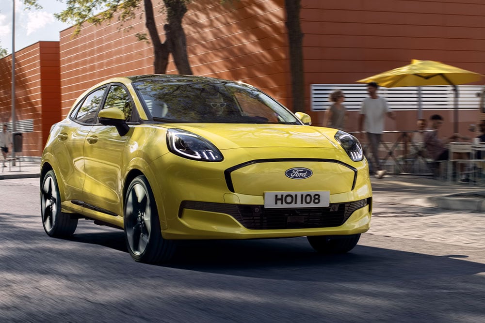 Čelní pohled na žlutý elektrický Ford Puma Gen-E® jedoucí po městské ulici.