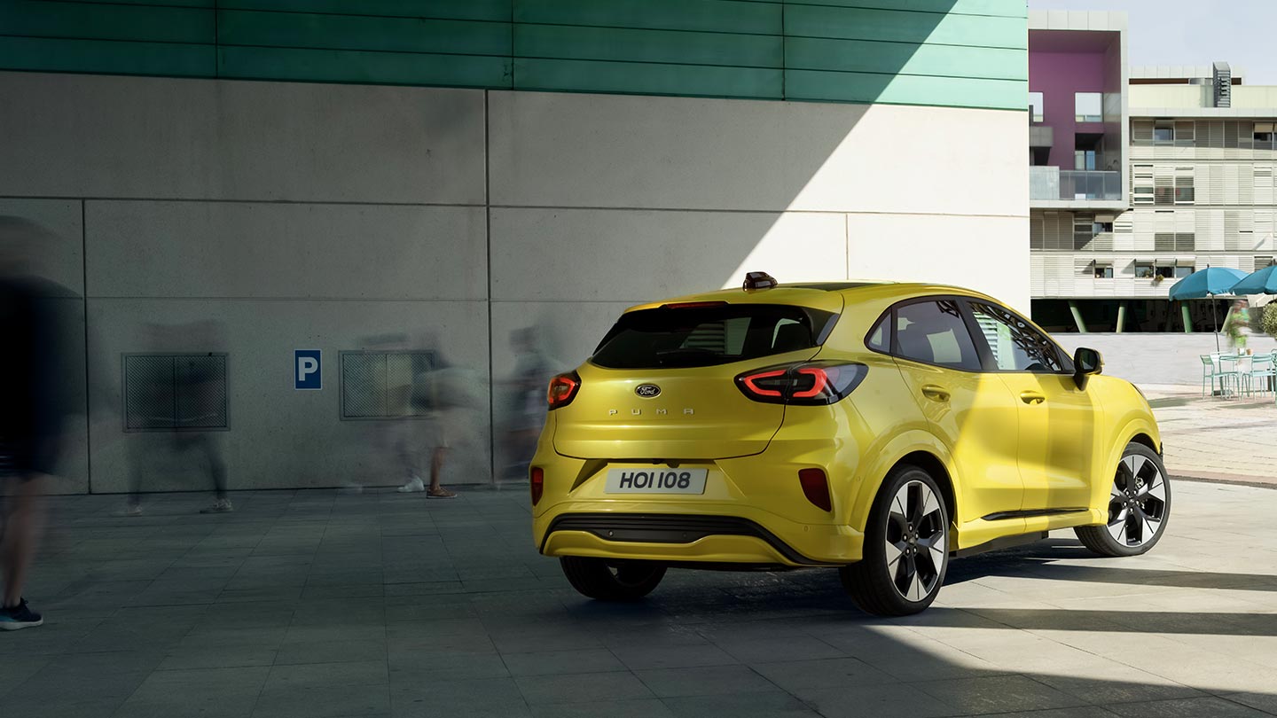 Zadní pohled na žlutý elektrický Ford Puma Gen-E ® zaparkovaný pod mostem.