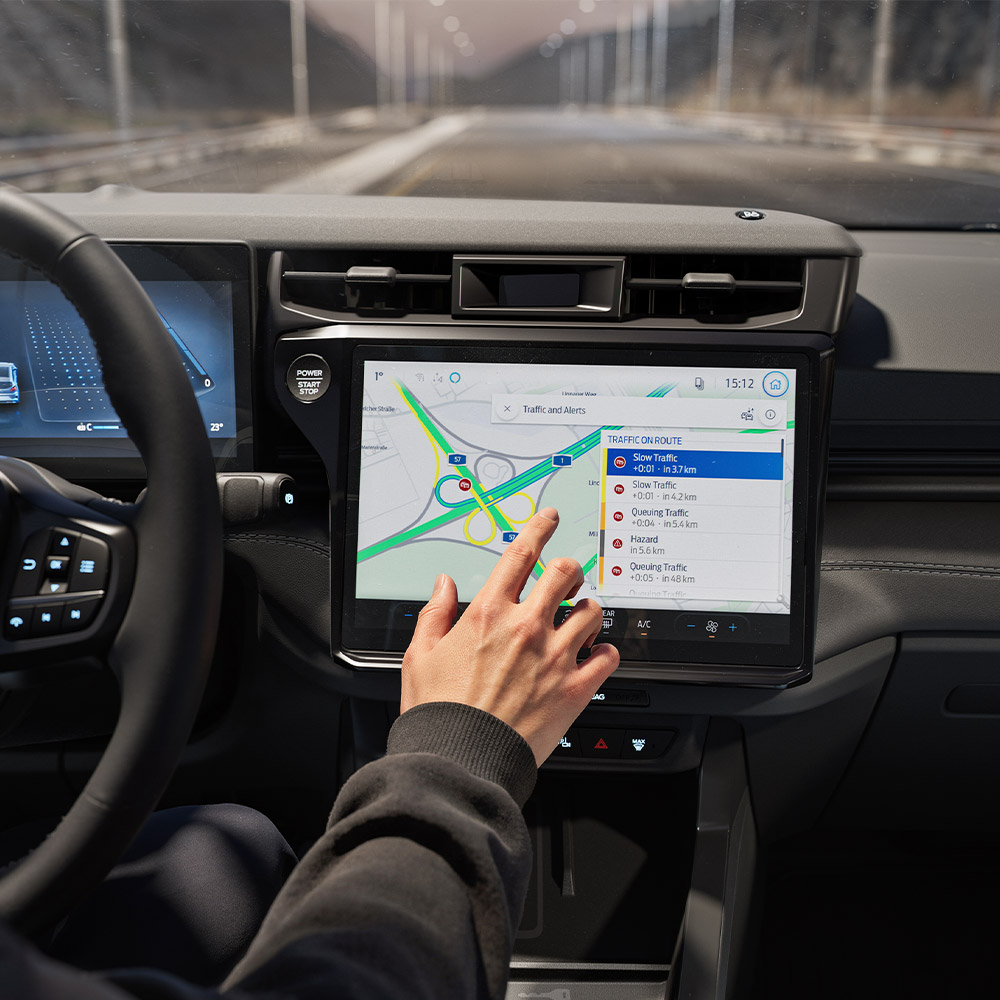 Řidič používá online navigaci na digitální obrazovce ve voze Ford Puma Gen-E BlueCruise Edition.