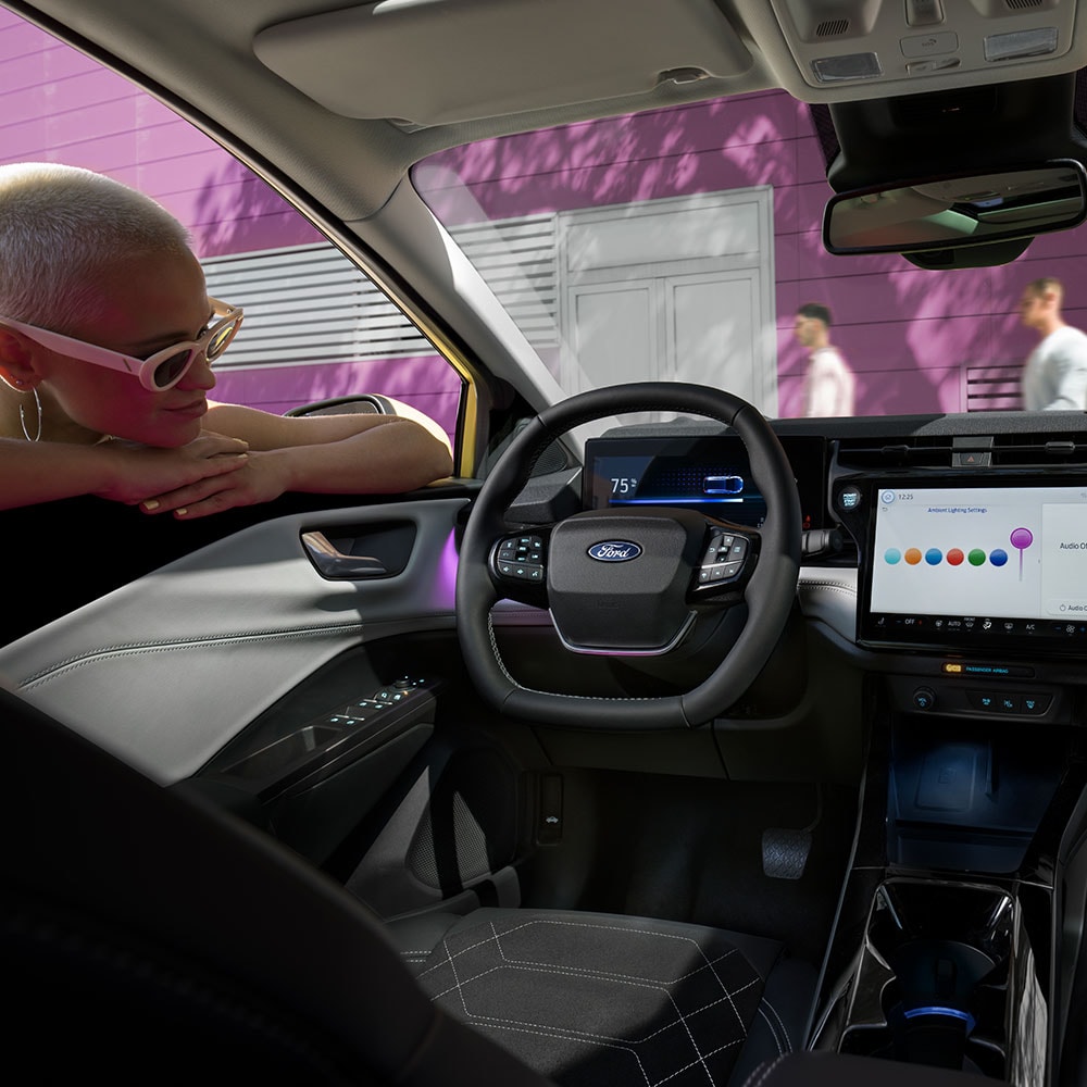 Člověk se dívá oknem do interiéru elektrického Fordu Puma Gen-E ® na velkou obrazovku infotainmentu.