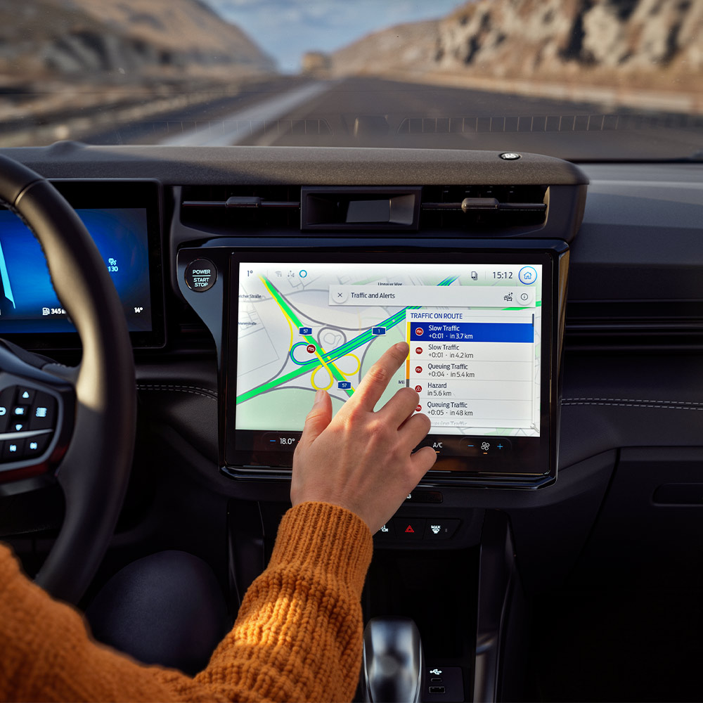 Řidič používá online navigaci na digitální obrazovce ve voze Ford Puma Gen-E BlueCruise Edition.