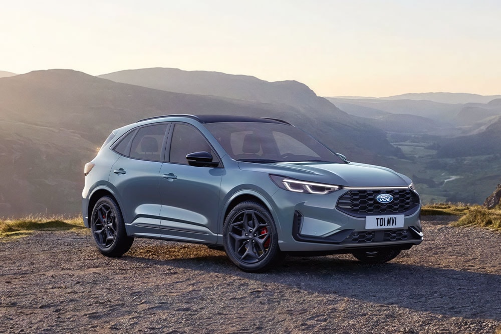 Šedý Ford Kuga zaparkovaný na štěrkové horské cestě při západu slunce.