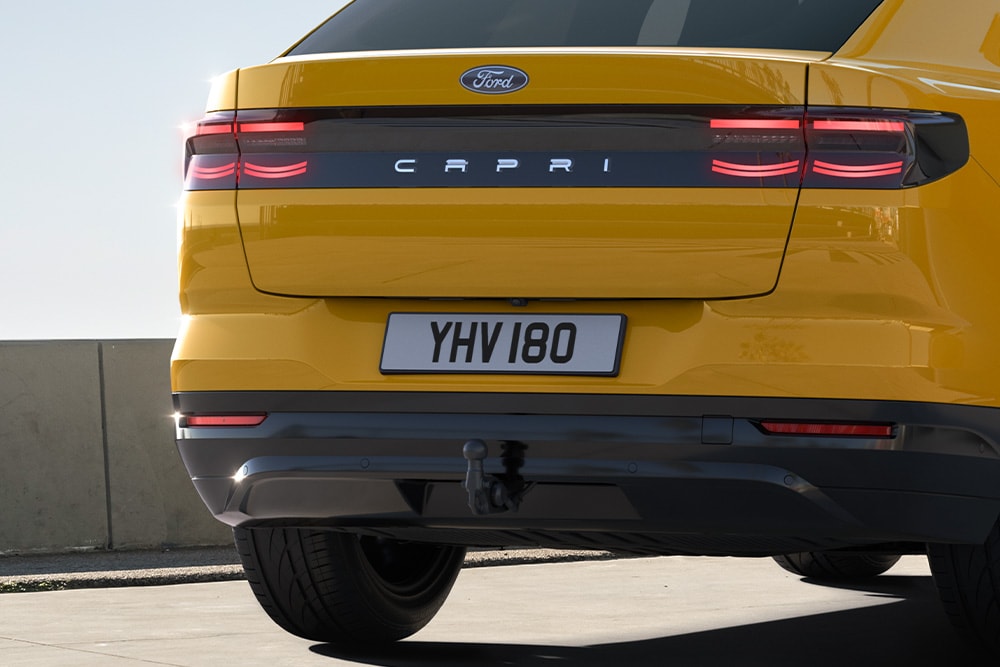 Pohled zezadu na žlutý Ford Capri® jedoucí po městské ulici.