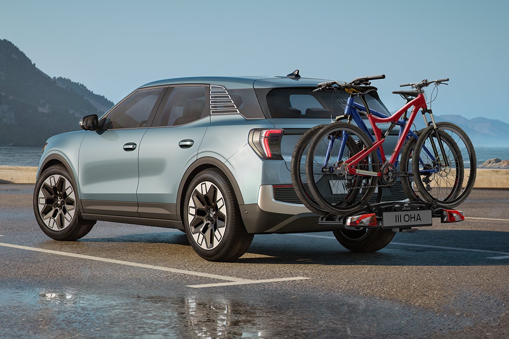 Modrý Ford Explorer jedoucí po polní cestě, s příčníky, nosičem kol na střechu a dvěma koly připevněnými na střeše.