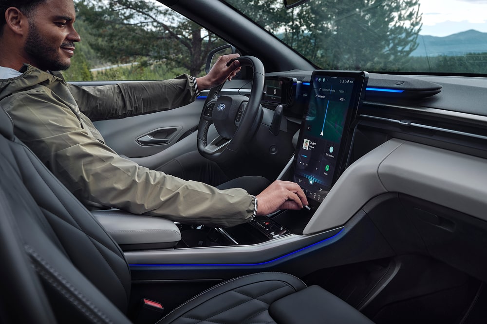 Řidič používá dotykový displej infotainmentu uvnitř rodinného SUV Ford Explorer.
