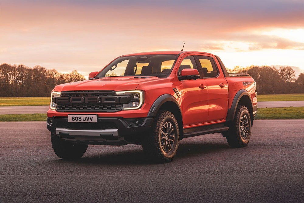 Oranžový pick-up Ford Ranger Raptor zaparkovaný v malebné krajině.