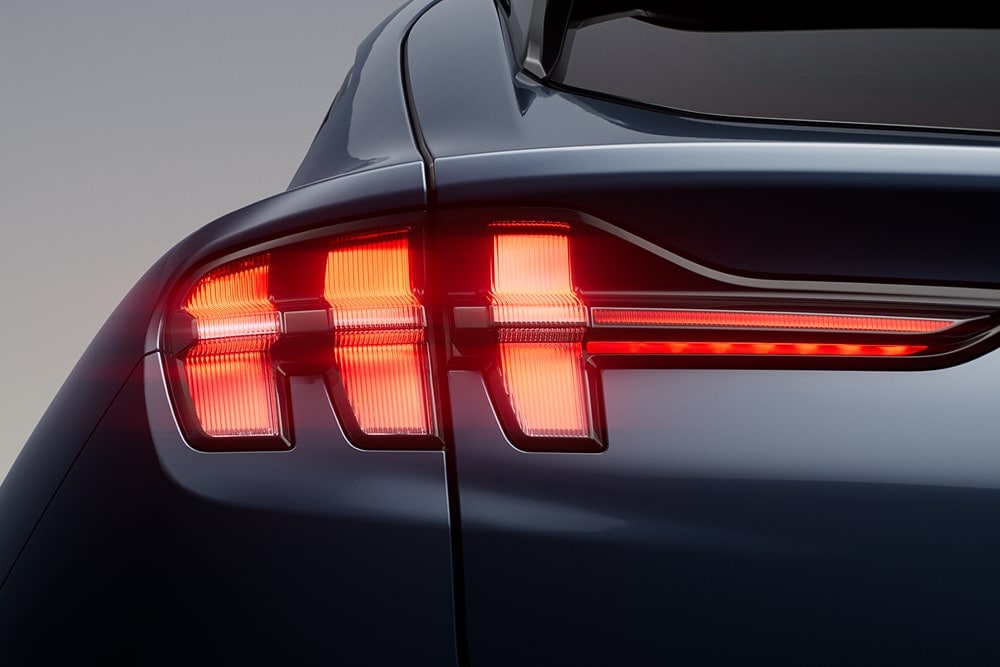 Detail na rozsvícená zadní světla sportovního vozu Ford Mustang Mach-E.