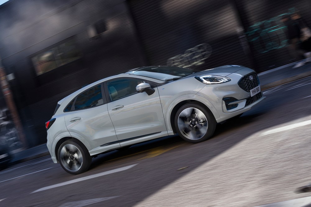 Šedý Ford Puma z nabídky kompaktních vozů Ford jede po městské ulici.