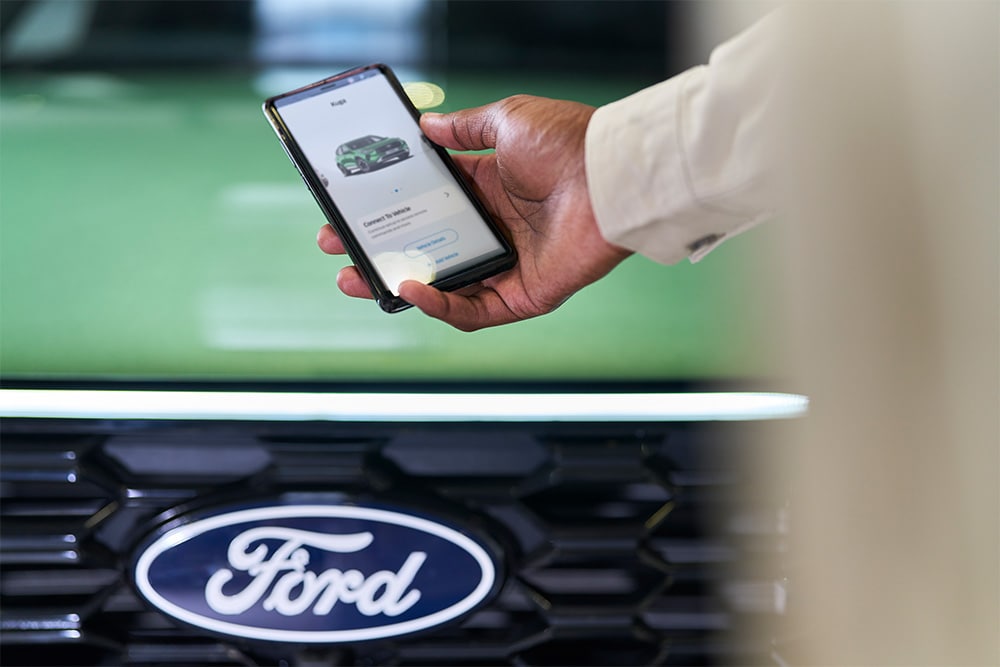 Muž dívající se na smartphone se zobrazenou aplikací FordPass