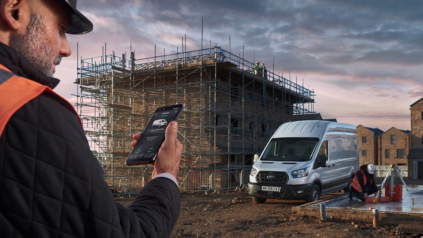 Man looking at his phone on building site with Ford Transit