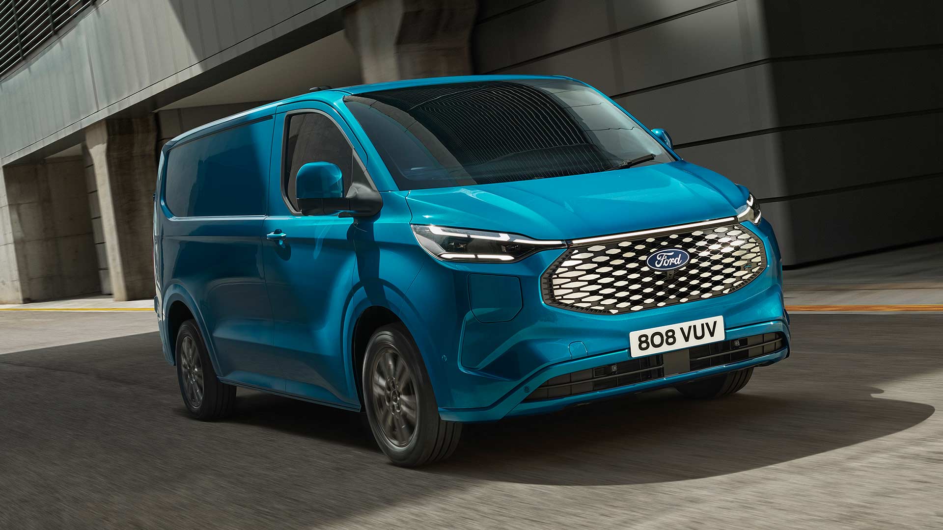 Modrá elektrická dodávka Ford E-Transit Custom při jízdě.