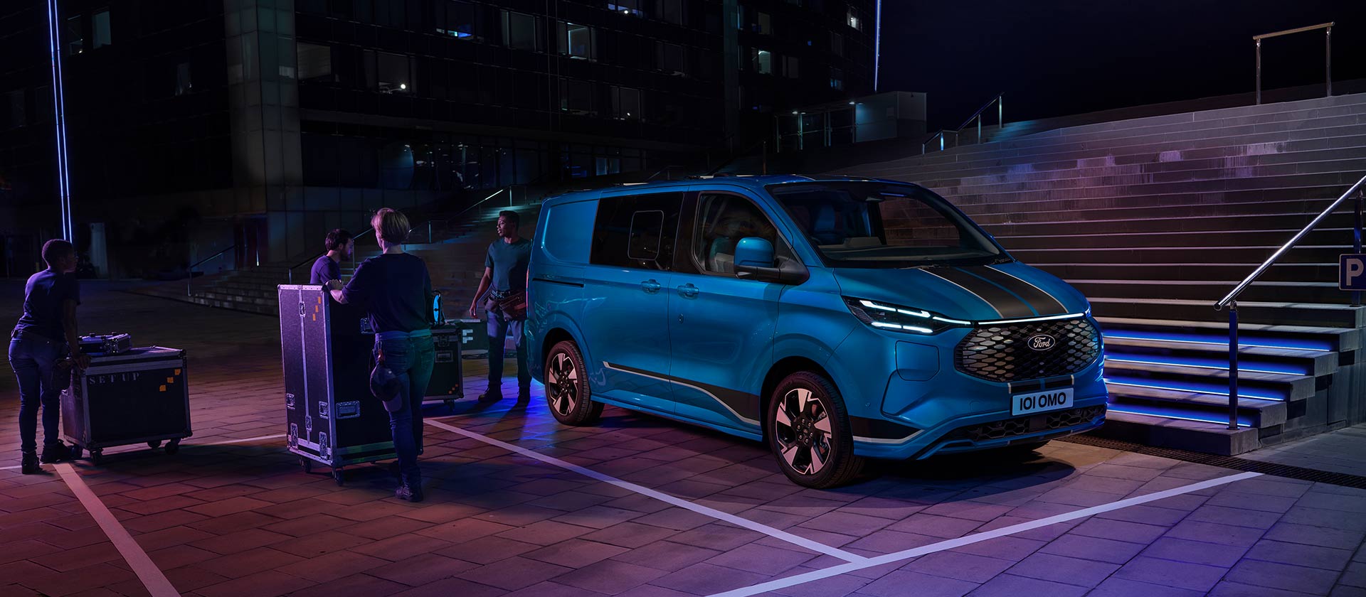Modrá elektrická dodávka Ford E-Transit Custom při nakládání v noci. 
