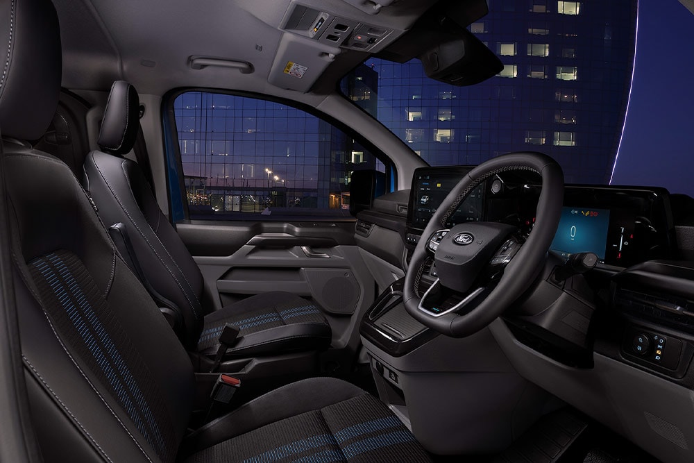 Interiér elektrické dodávky Ford E-Transit Custom se sedadly řidiče a spolujezdce.