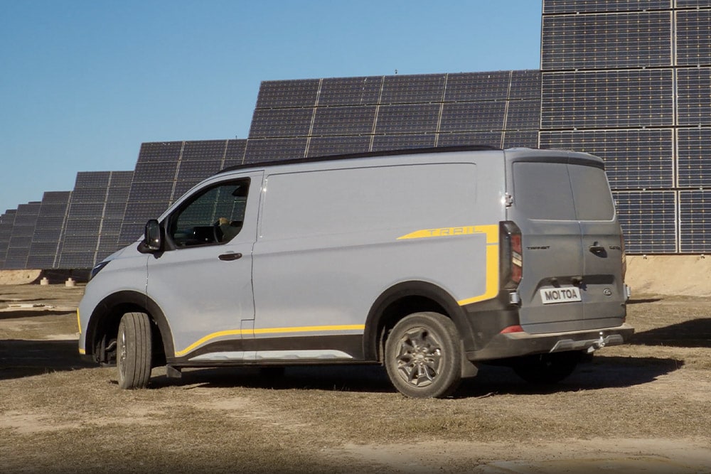 Šedá dodávka Ford Transit Custom Trail se žlutými polepy.