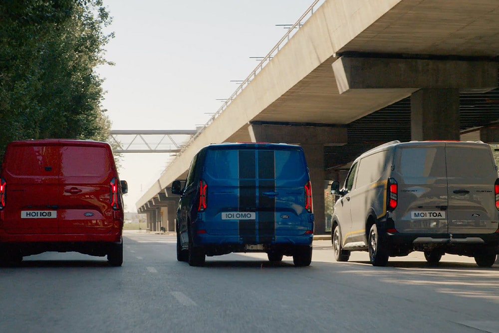 Tři dodávky Ford Transit Custom jedoucí po silnici.