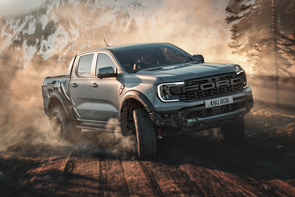 Ford Ranger Raptor v jízdním režimu Baja projíždí po nezpevněné cestě. V pozadí je horská krajina.