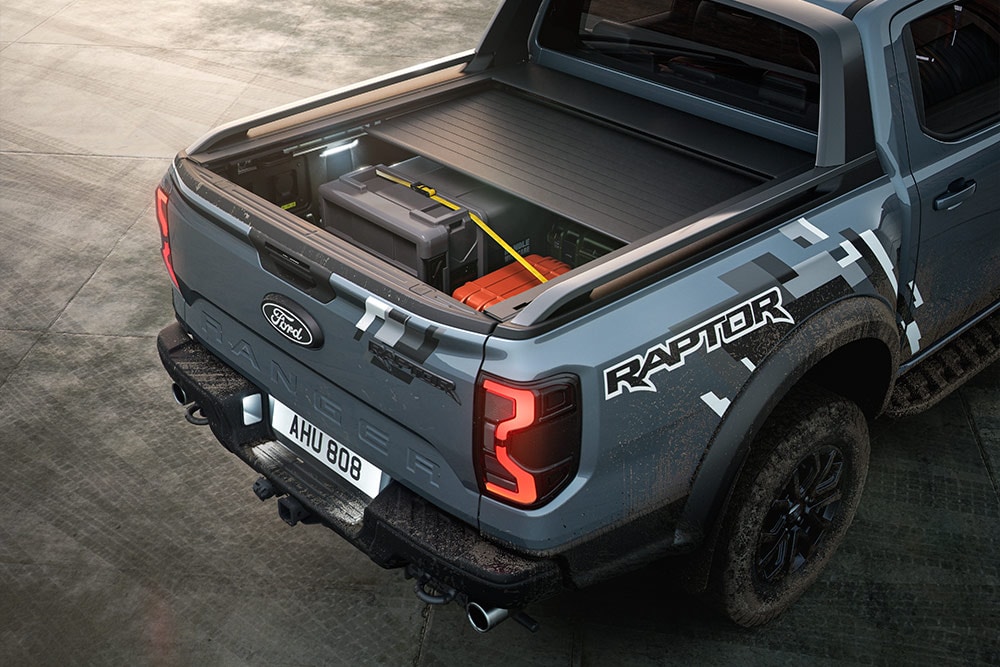 Pohled zezadu na zaparkovaný modrý Ranger Raptor s elektricky ovládaným rolovacím krytem korby.