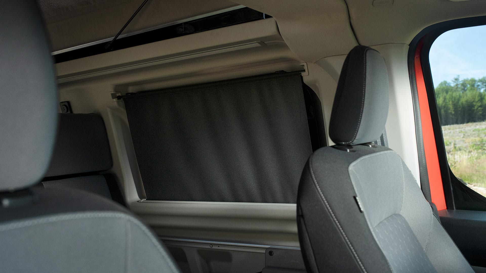 Interiér obytného vozu Ford Transit Custom Nugget se zatemňovacími roletami v zadních oknech.