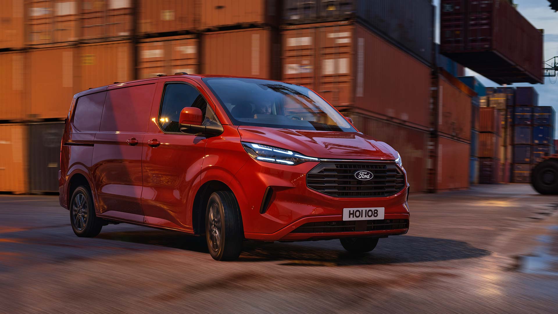 Červená dodávka Ford Transit Custom projíždí přístavištěm.