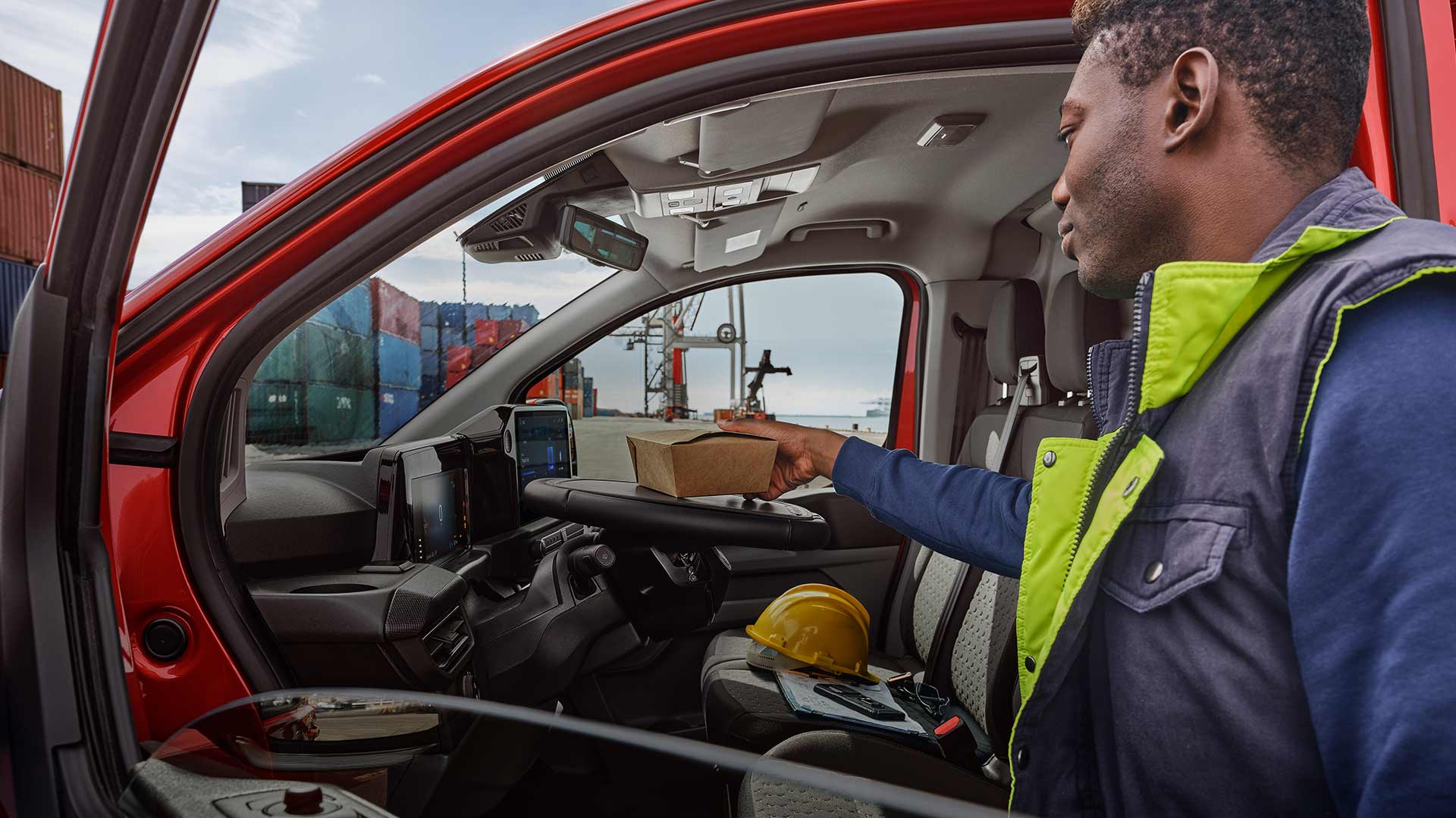 Osoba pokládá oběd na sklopný volant vozu Ford Transit Custom.
