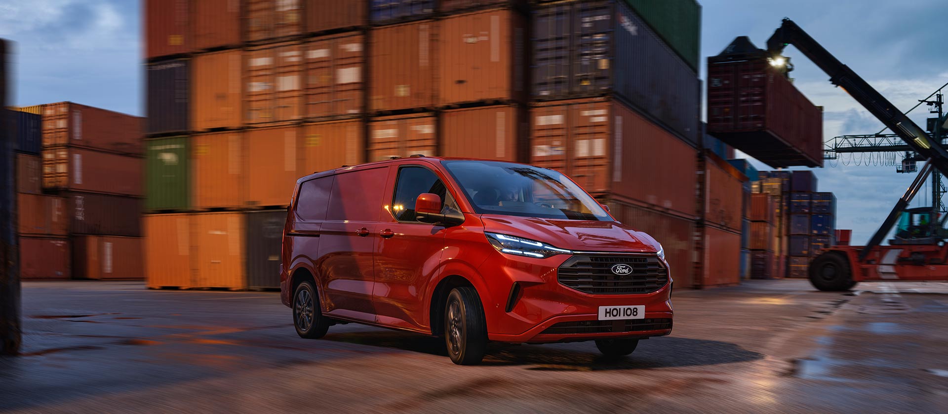 Červená dodávka Ford Transit Custom projíždí přístavištěm.
