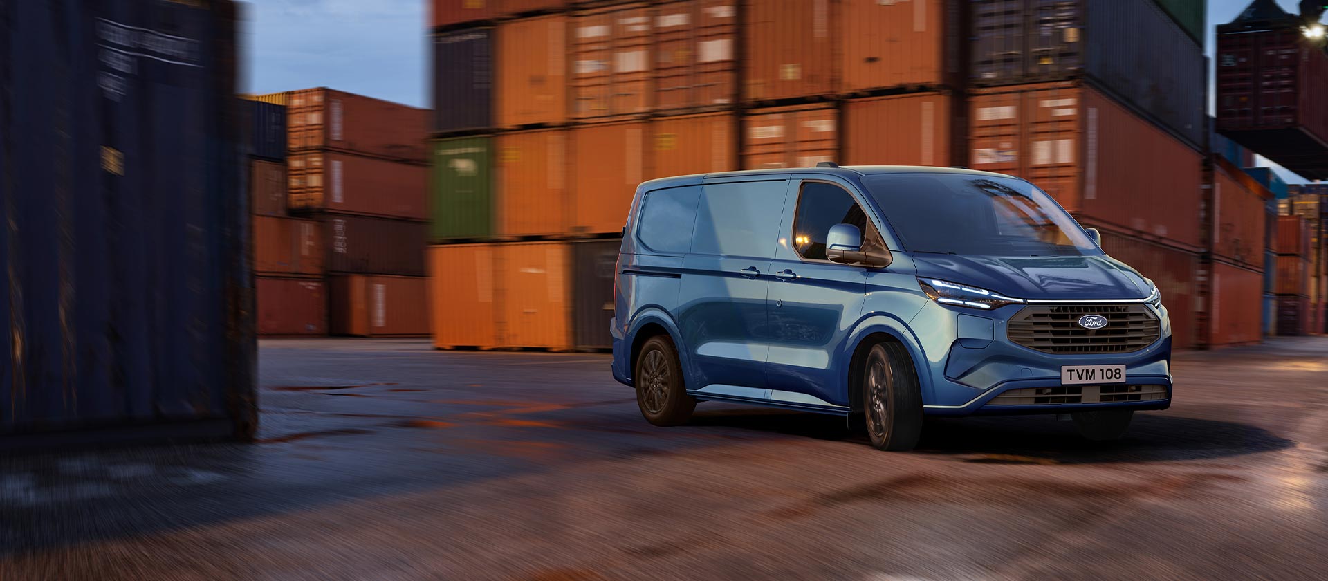 Modrý Ford Transit Custom Plug-in Hybrid projíždí přístavištěm.
