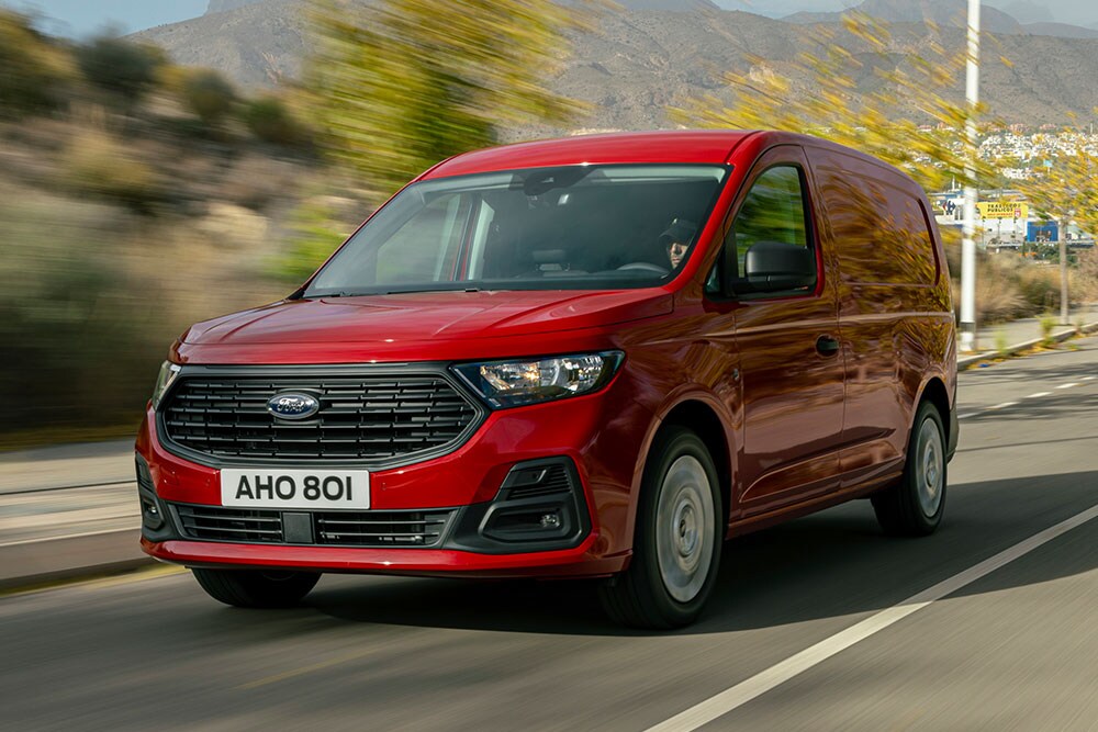 Ford Transit Connect s vyobrazenou přední maskou a automatickými světlomety jede po silnici.